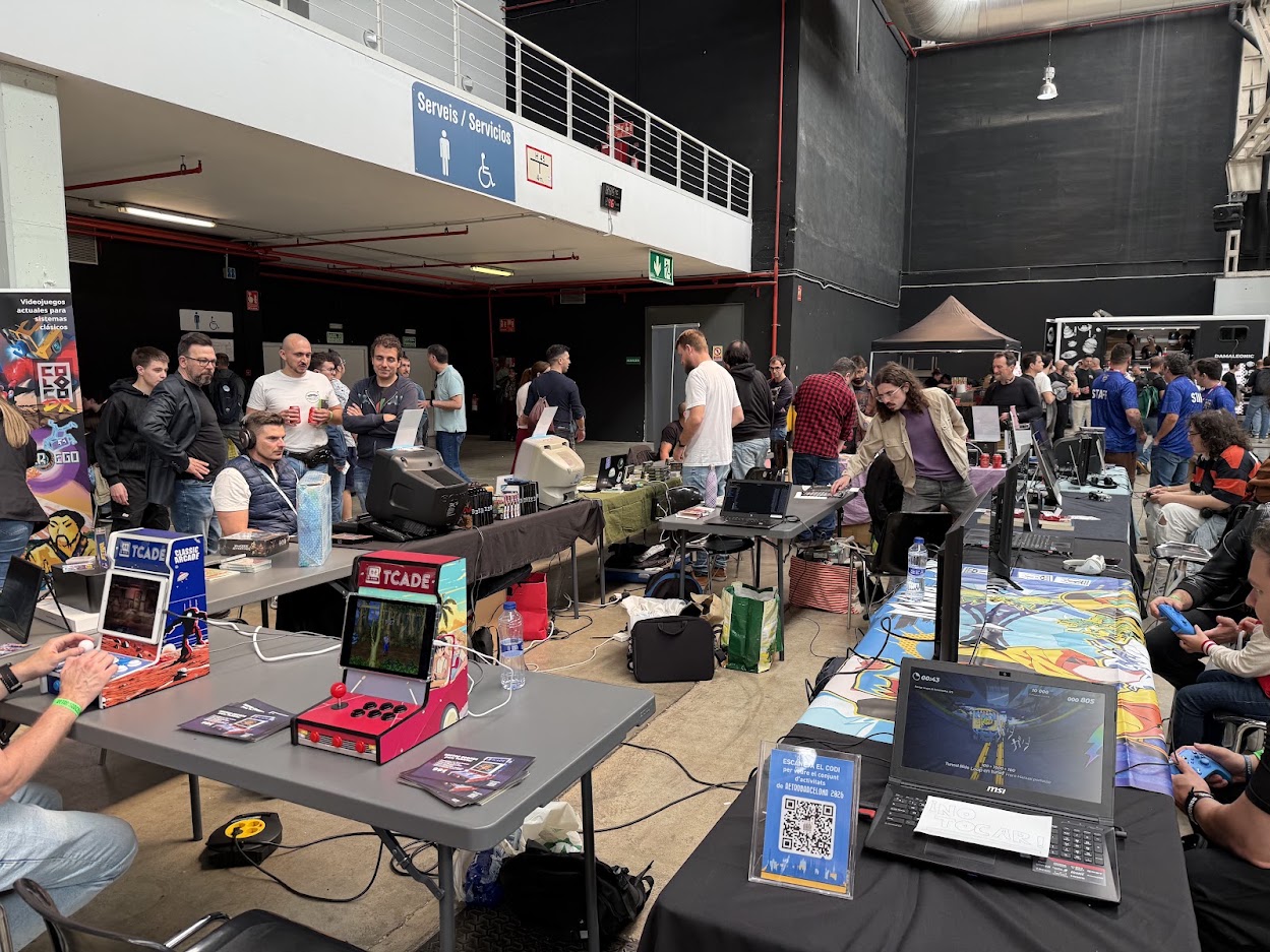 Visitors playing mini arcade cabinets and CRT setups on the exhibitor floor at Retro Barcelona in La Farga de l'Hospitalet.